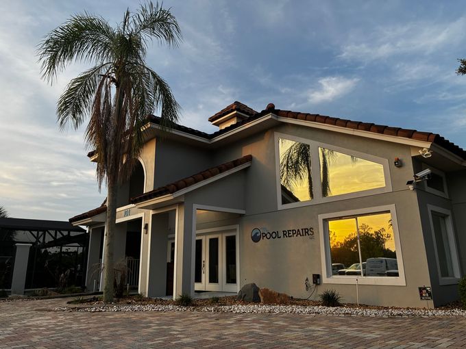 Modern two-story house exterior with large windows, palm tree, and warm sunset light