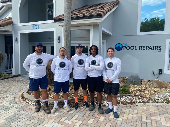 Five pool repair workers standing outside a building with a pool repairs sign