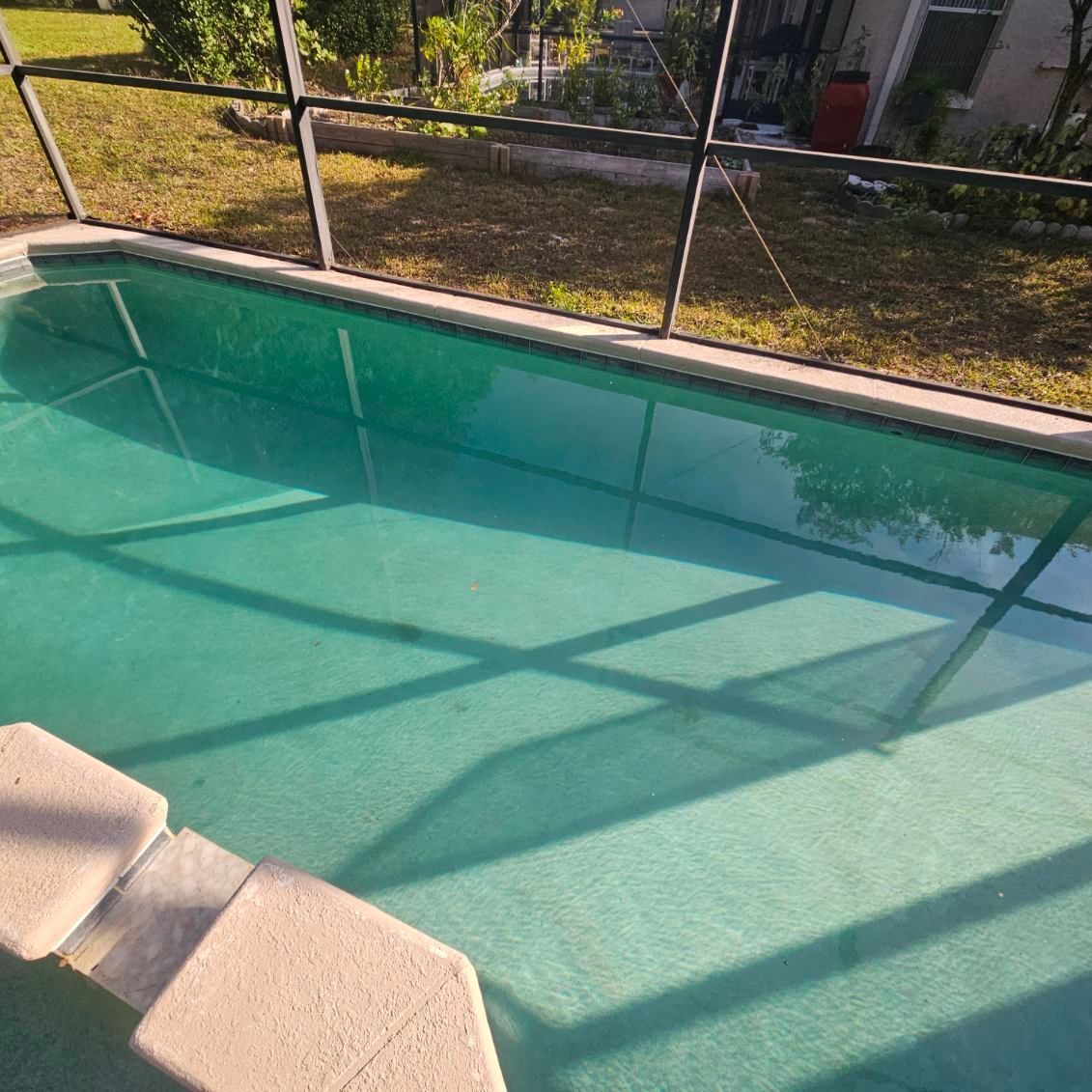 A rectangular swimming pool filled with turquoise water, with steps leading into the pool. 