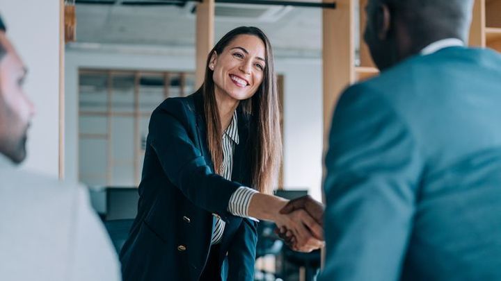 A woman is shaking hands with a man in a suit.