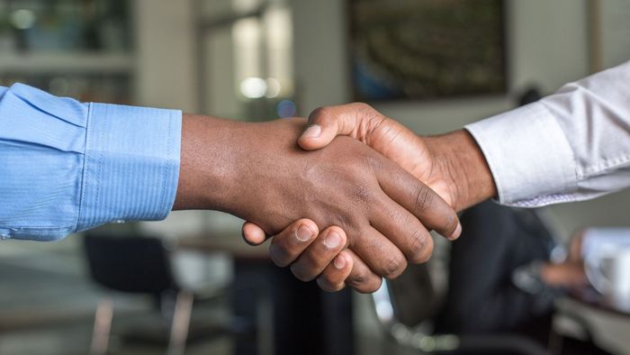 Two men are shaking hands in an office.