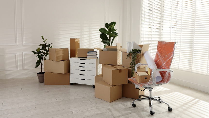 Packed moving boxes in a bright office with plants and a red swivel chair
