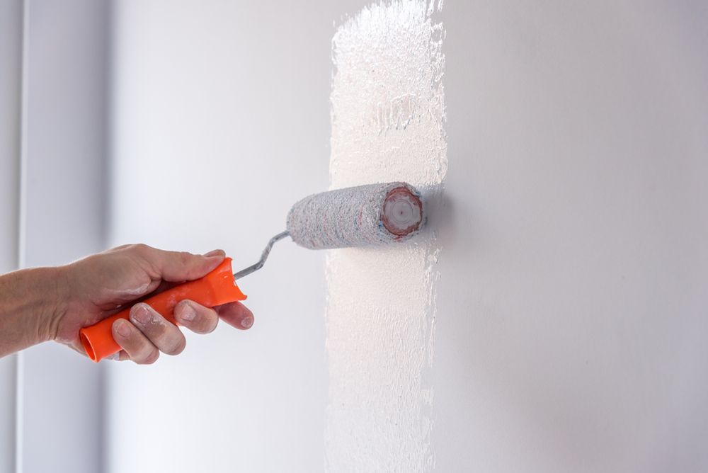 A Person Is Painting A Wall With A Paint Roller — Aaron Lee Painting Pty Ltd In Townsville City, QLD