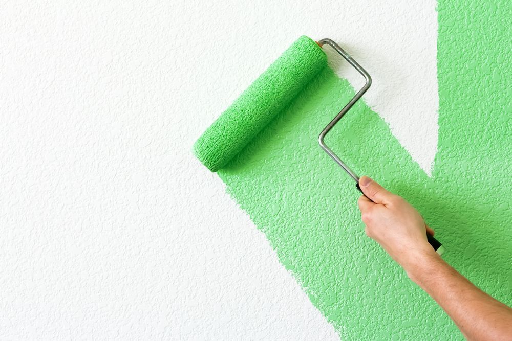 A Person Is Painting A Wall With A Green Paint Roller — Aaron Lee Painting Pty Ltd In Douglas, QLD
