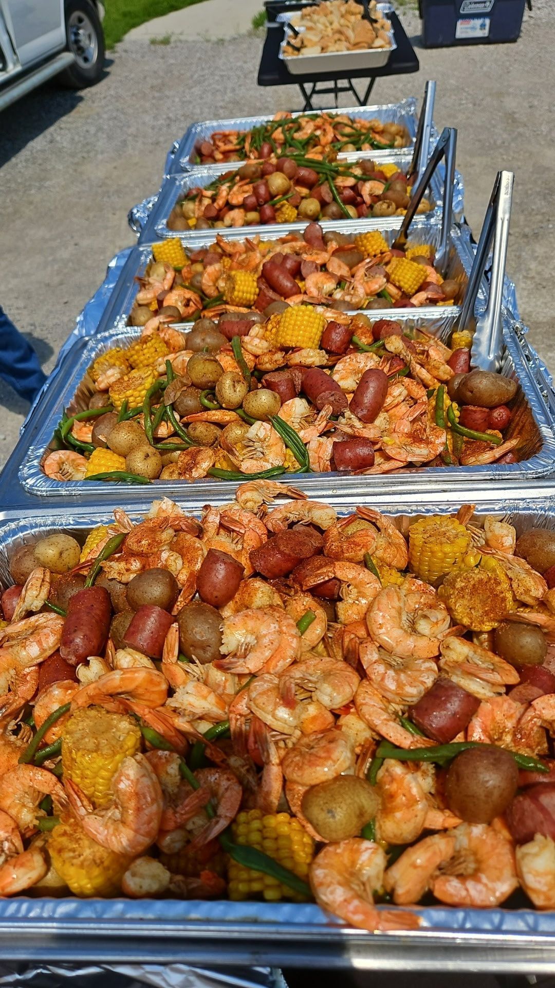 Trays of roasted sausage and vegetables at an outdoor food buffet line