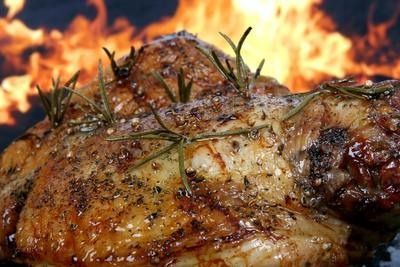 Grilled roast meat with rosemary, sizzling in front of a bright flame