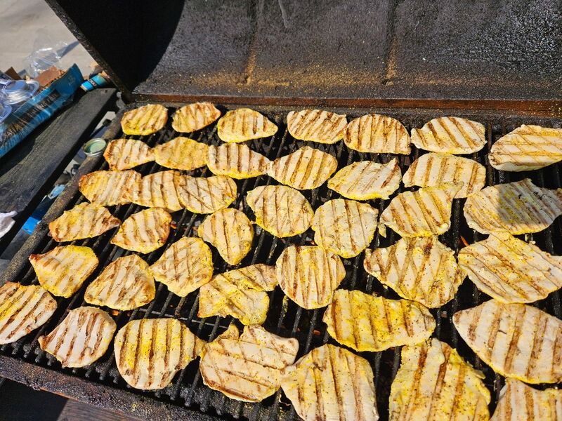 Grill covered with rows of yellow-striped grilled sandwiches or wraps cooking on a barbecue grate