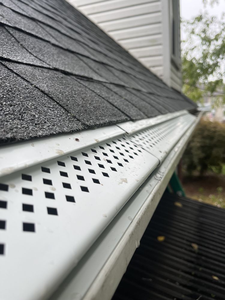 Close-up of gray roof shingles and white perforated soffit on a house exterior