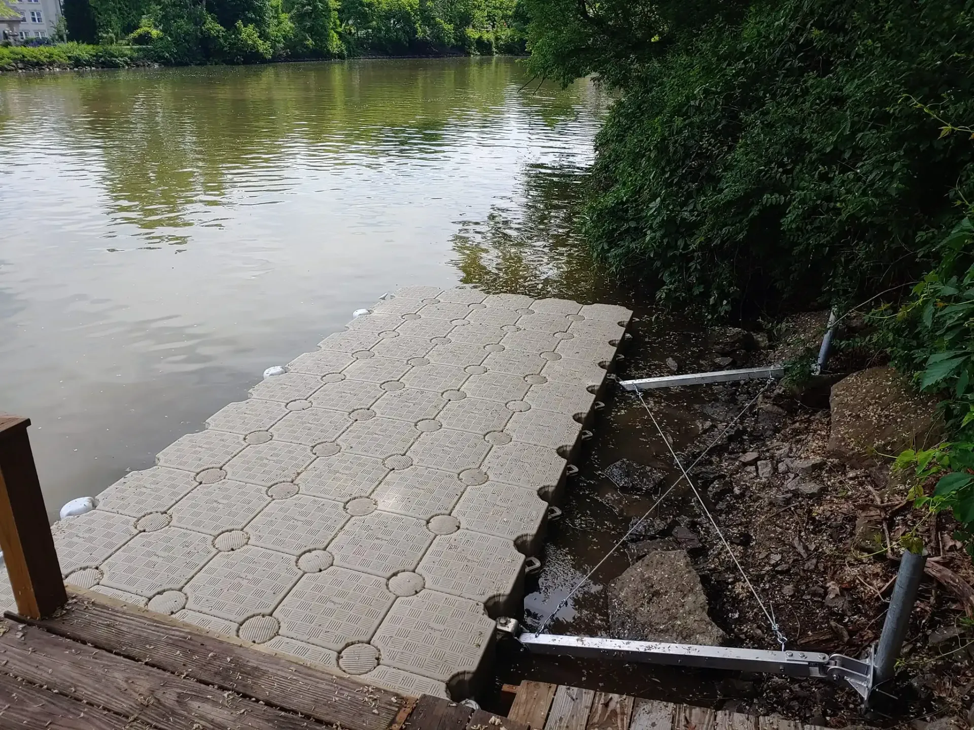 Floating dock platform by a calm river, with trees and muddy shore nearby