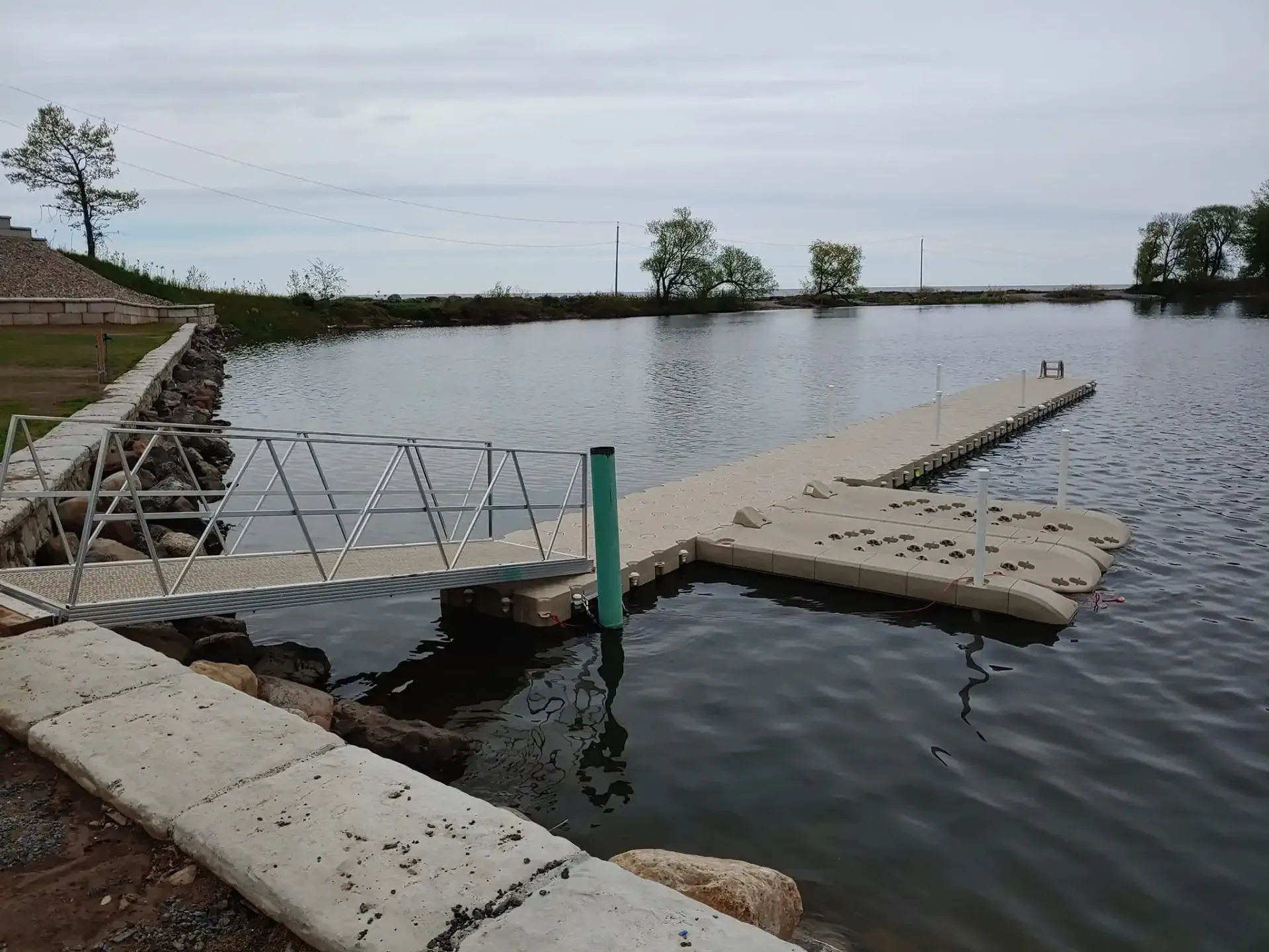 Floating dock with a gangway extending into a calm lake under an overcast sky