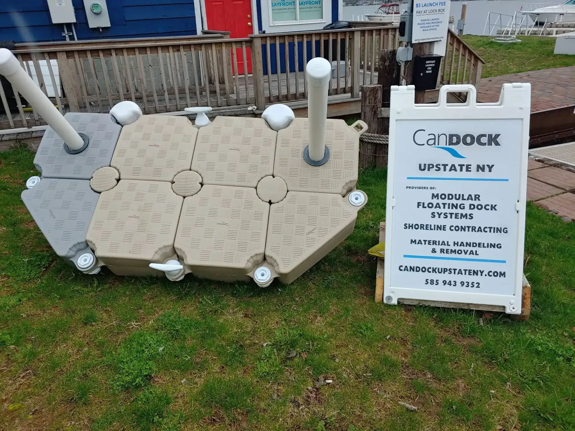 Wooden paw-shaped platform with white posts beside a sign reading “LILY’S UPDATE NY” outdoors
