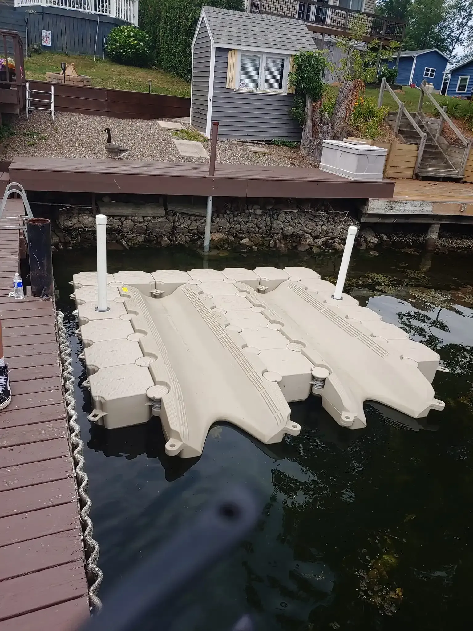 White floating dock sections moored beside a wooden pier in a marina basin