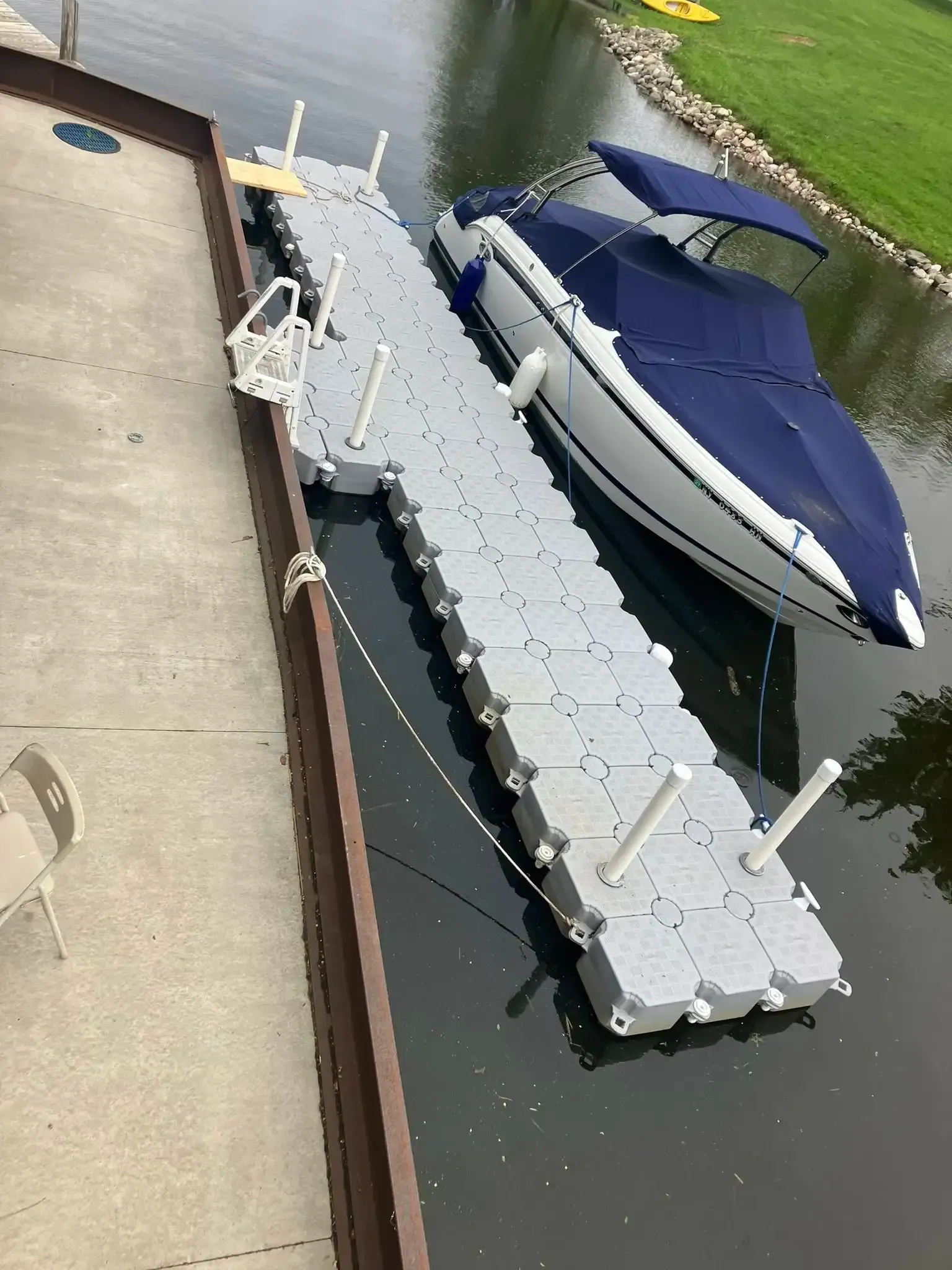 Dock with white floats beside a blue-covered boat in calm marina water