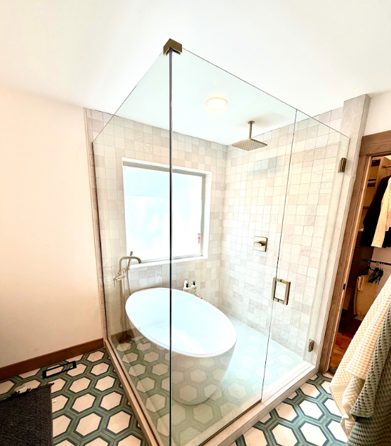 Modern bathroom with glass shower enclosure, white oval tub, tiled walls, and patterned floor.