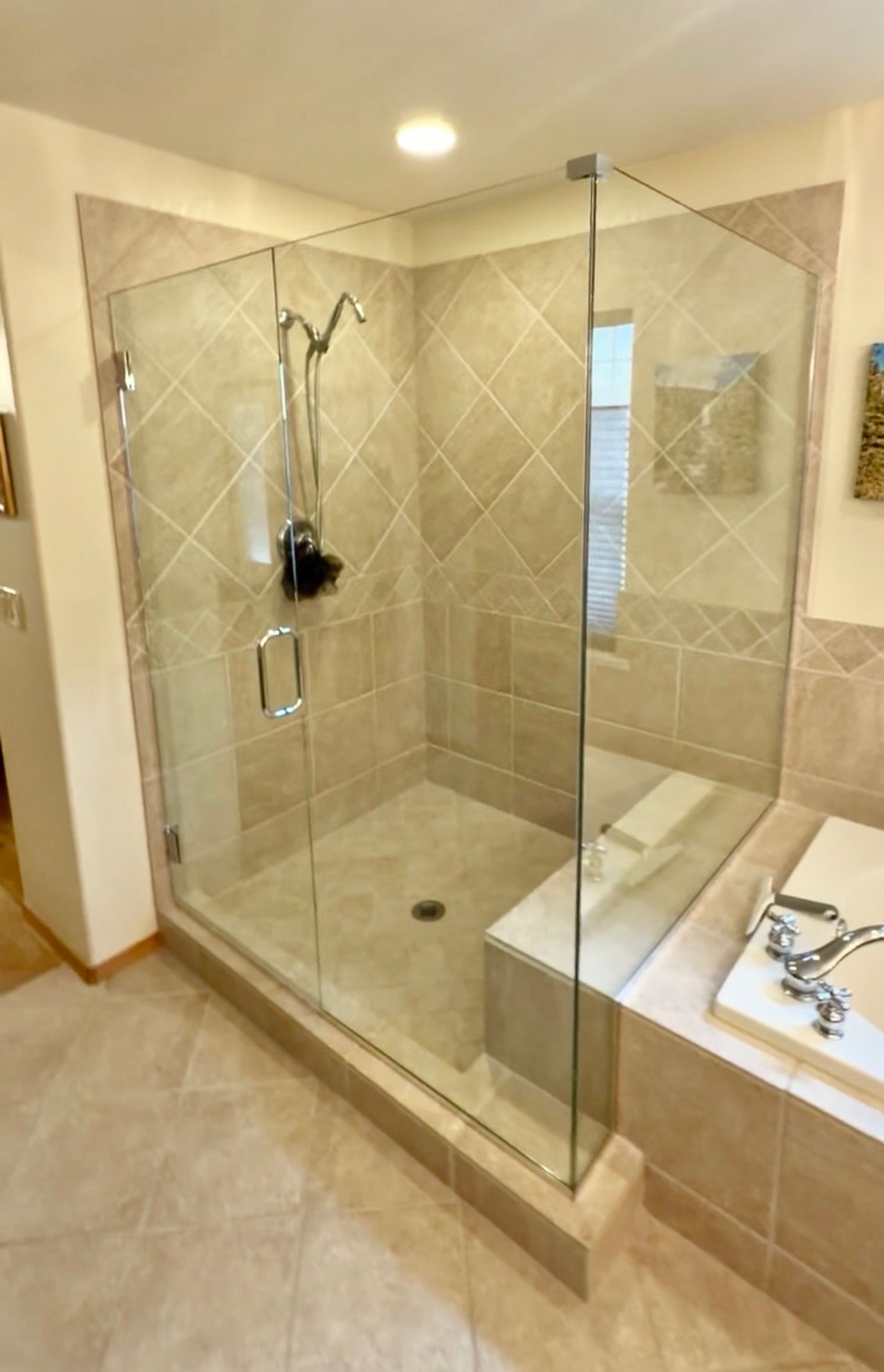 Modern beige bathroom with glass-enclosed walk-in shower and tiled tub surround