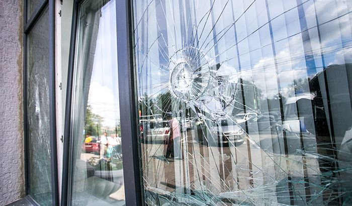 A large, cracked window pane reflects the exterior street scene and building structure.