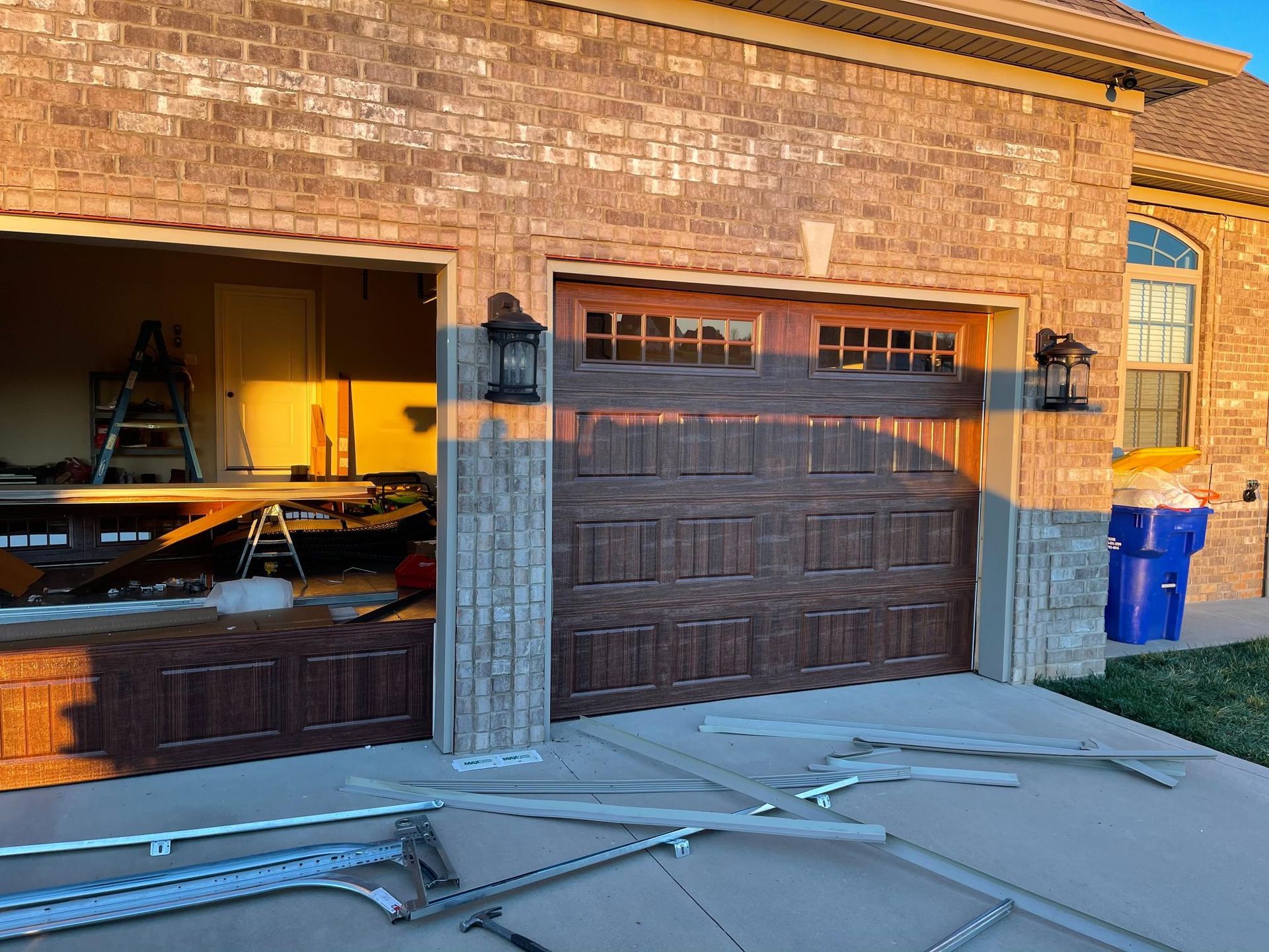 Garage exterior with a partially open door, brown brick, and debris on the ground.