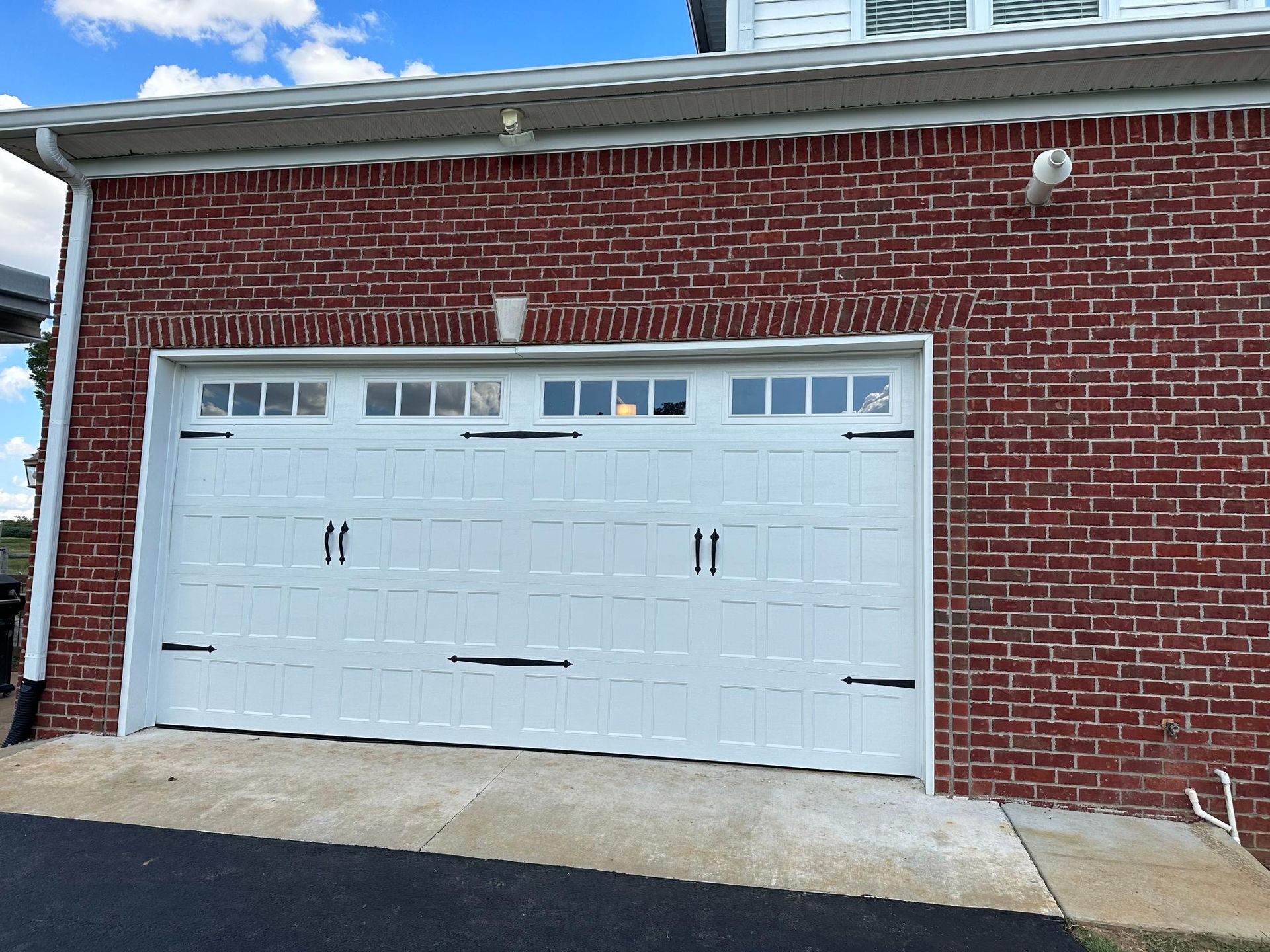 White garage door on a red brick building; overcast day.