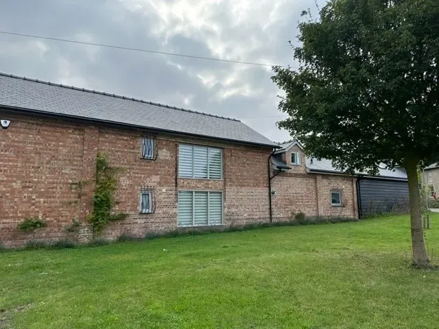 A large brick building with a lot of windows and a tree in front of it.