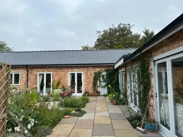 A brick house with a slate roof and a walkway leading to it.