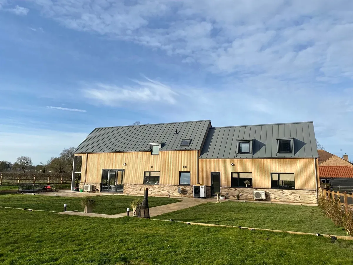 A large house with a metal roof is sitting on top of a lush green field.