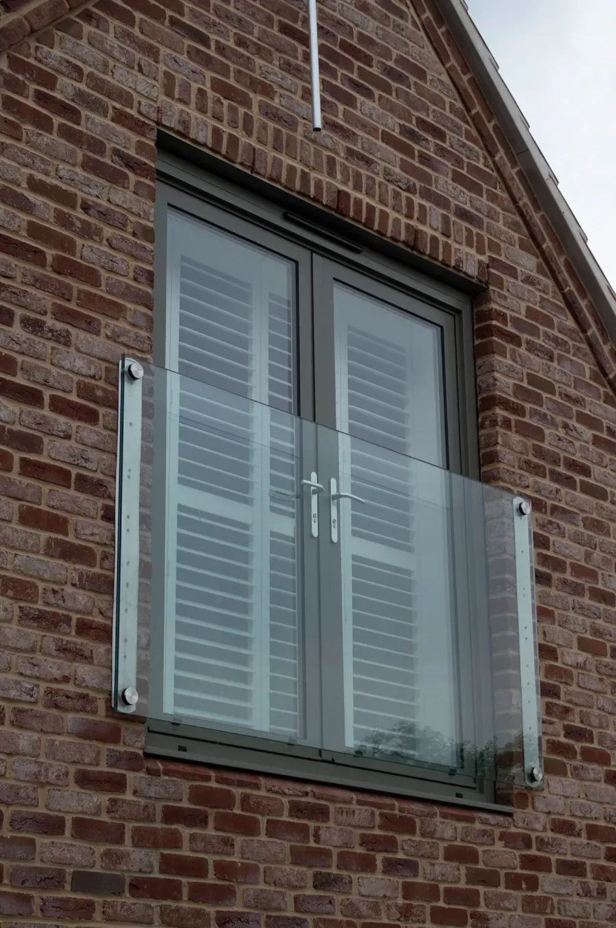 A brick building with a window and shutters on it.