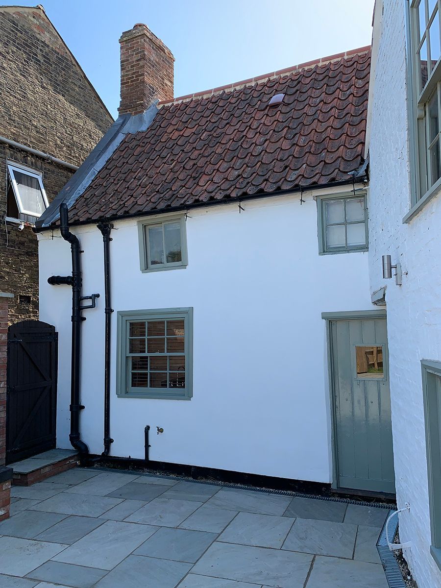 A small white house with a brick roof and a chimney
