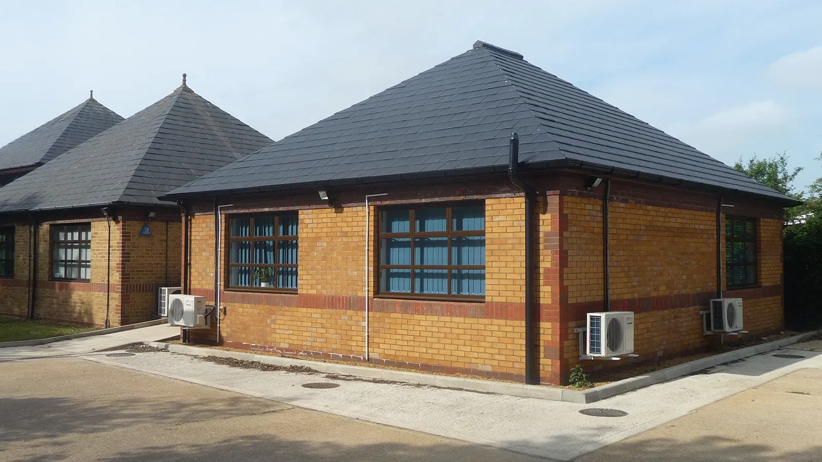 A brick building with a black roof and a lot of windows