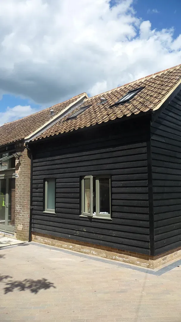 A small black house with a tiled roof and a lot of windows.