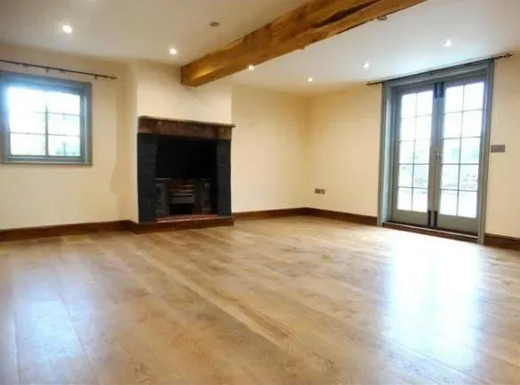 An empty living room with hardwood floors and a fireplace