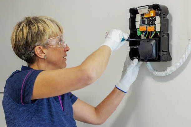 A certified female electrician performing EV charger installation at a residential property