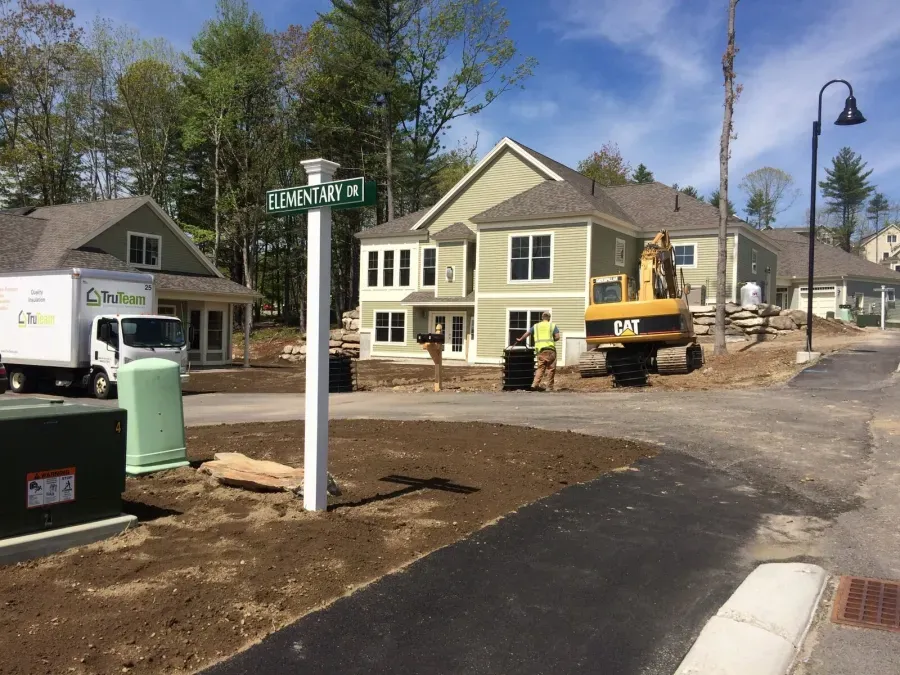 A cat excavator is parked in front of a house under construction