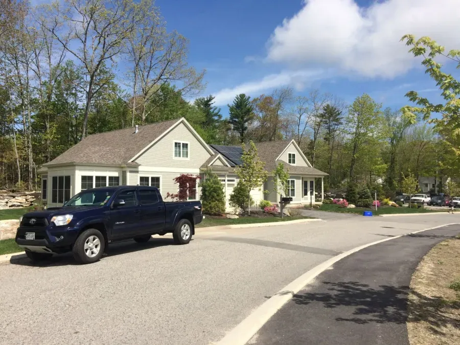 A black truck is parked on the side of the road in front of a house.