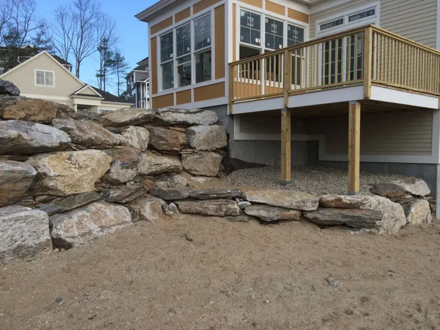 A house with a large rock wall in front of it