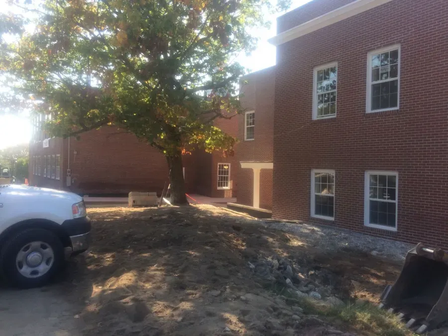 A white truck is parked in front of a brick building.