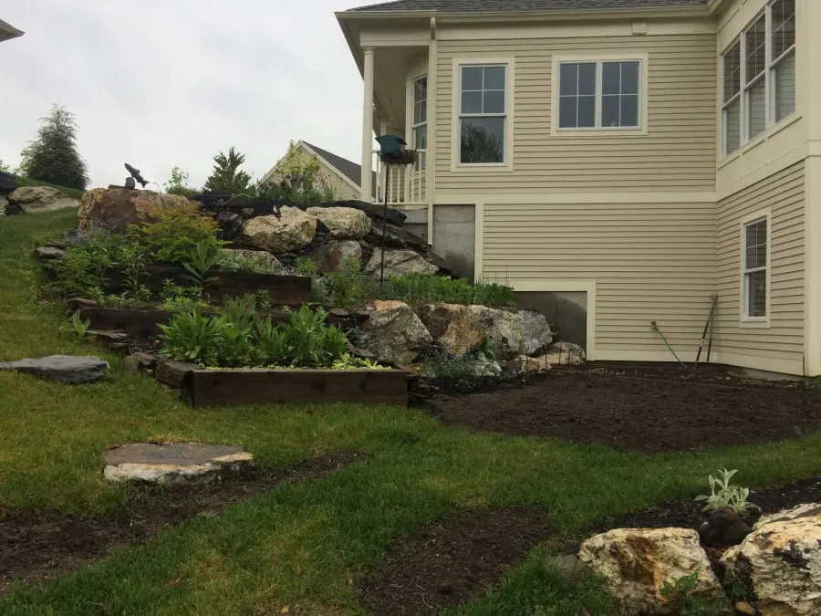 A house with a lot of rocks and plants in front of it.