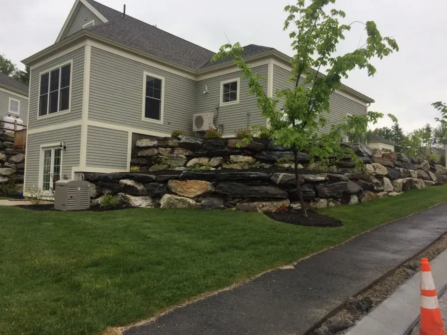 A large house with a large rock wall in front of it.