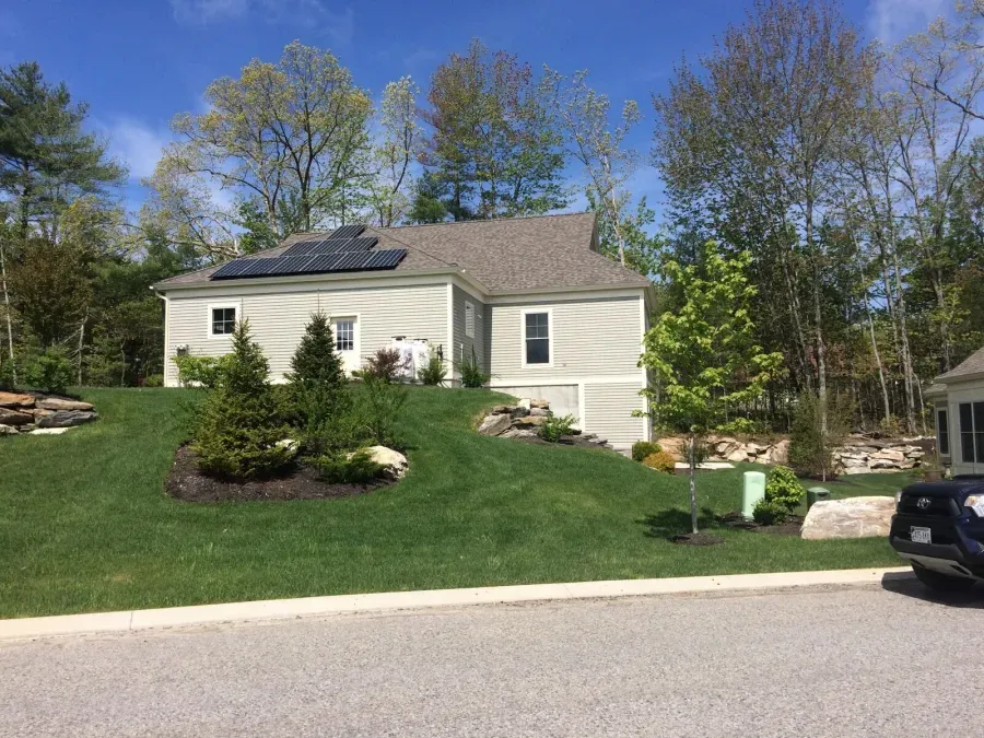 A house with solar panels on the roof and a car parked in front of it.