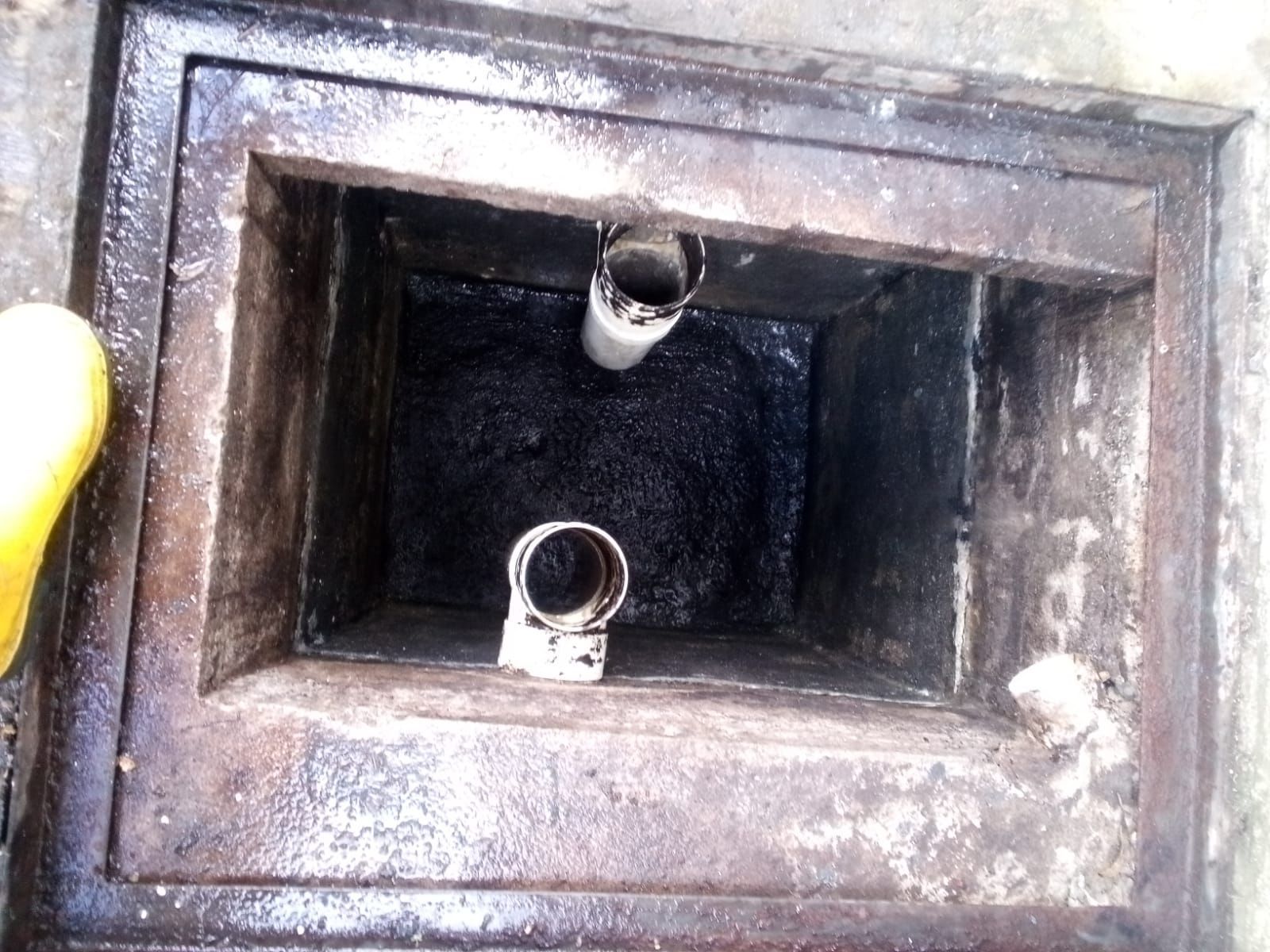 Dentro de un conducto metálico oscuro, una mano sostiene una linterna cerca de dos pequeños tubos que desembocan en un conducto rectangular.