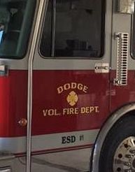 A red and white fire truck from the Dodge vol fire department is parked in a garage.