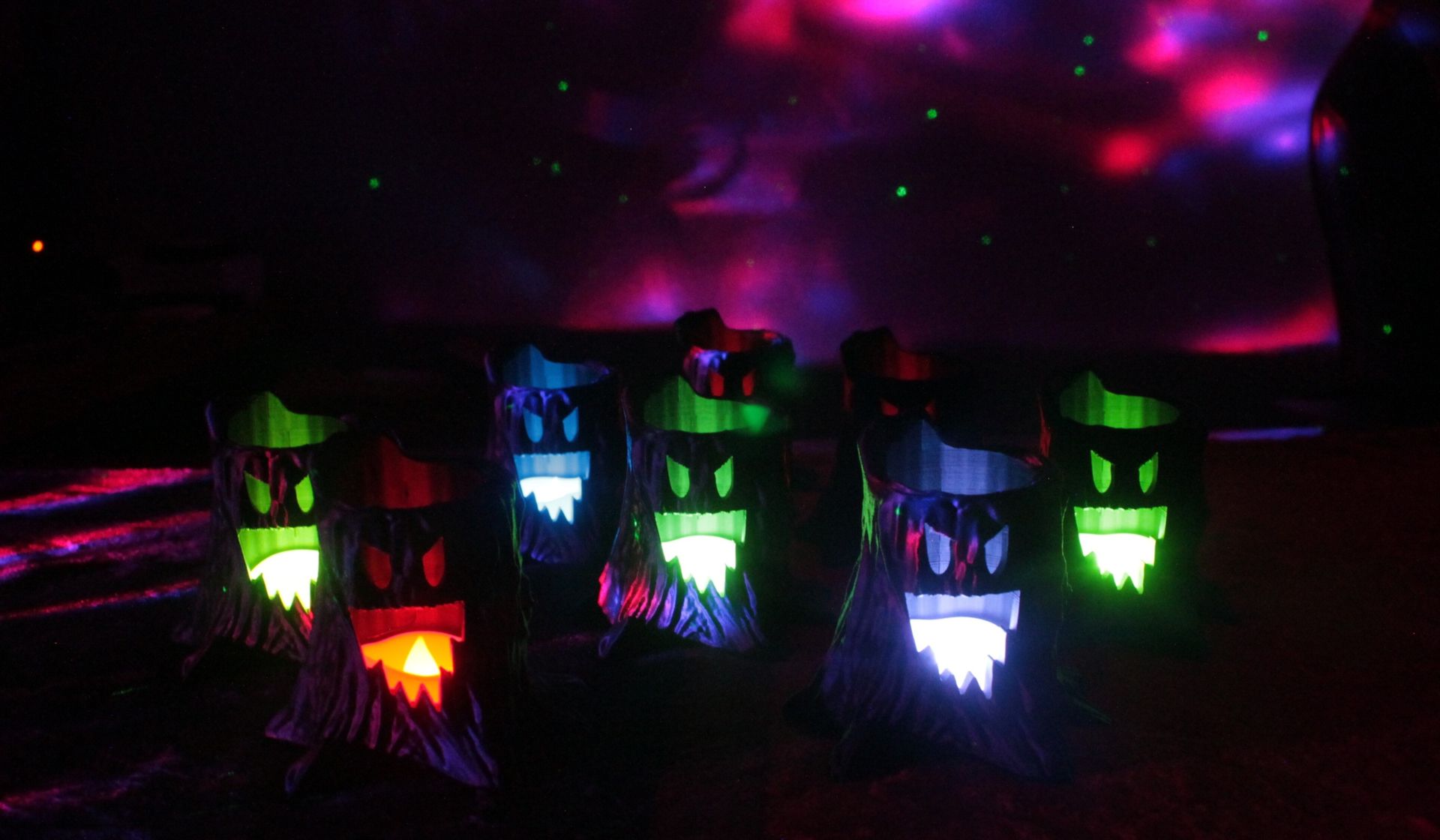 Glowing, colorful Halloween haunted tree decorations in a dark, spooky setting.
