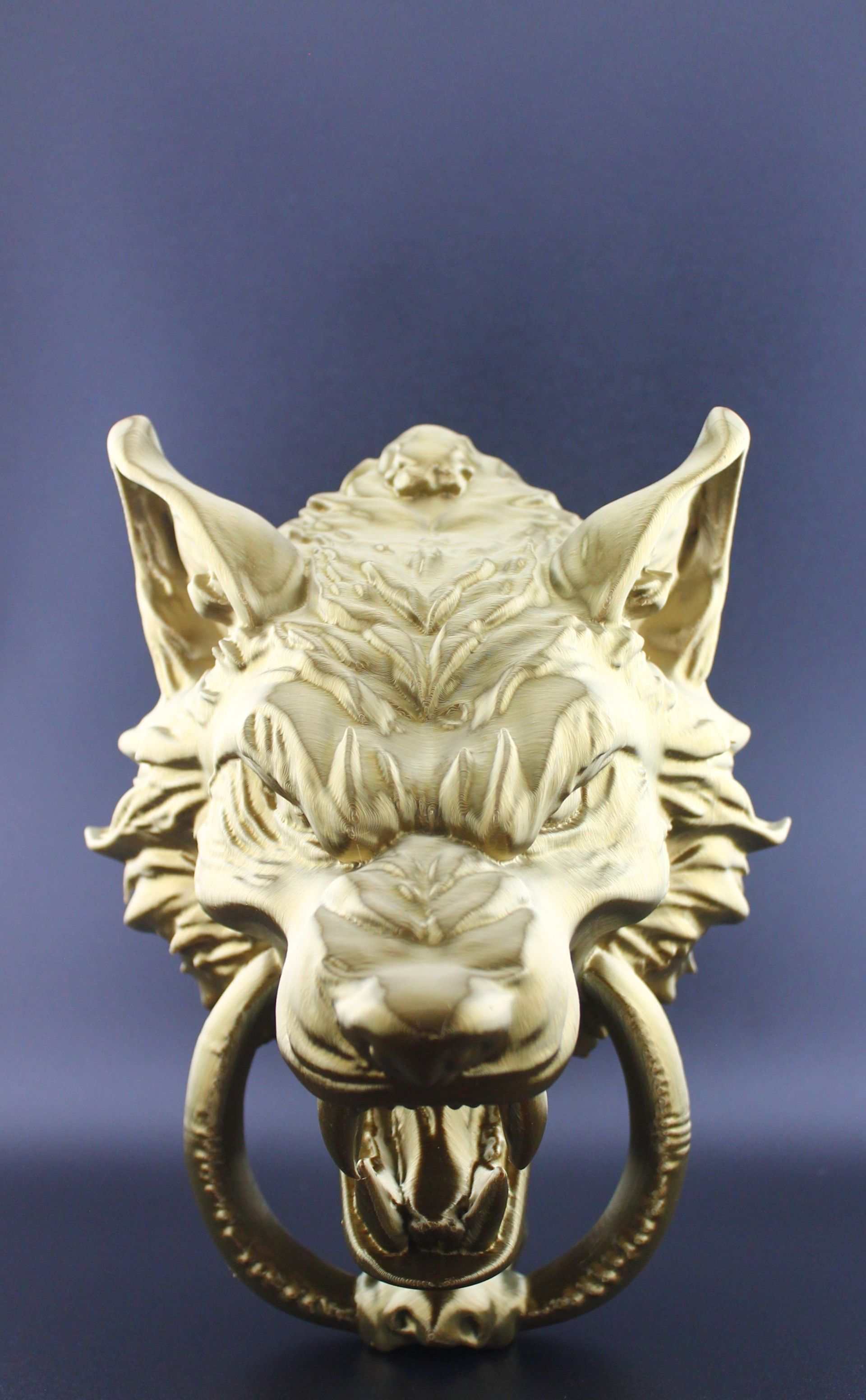 Gold-colored wolf head sculpture with snarling expression against a dark backdrop.
