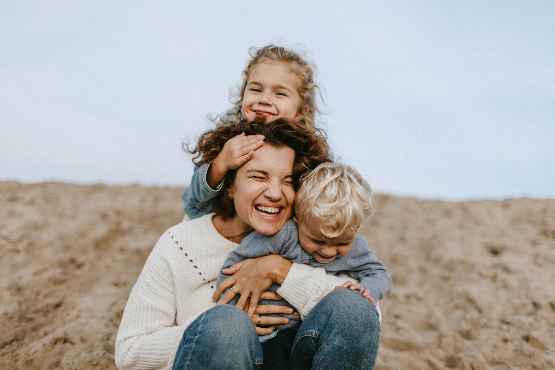 Family in a modern home, smiling and hugging. Two children are held by parents.