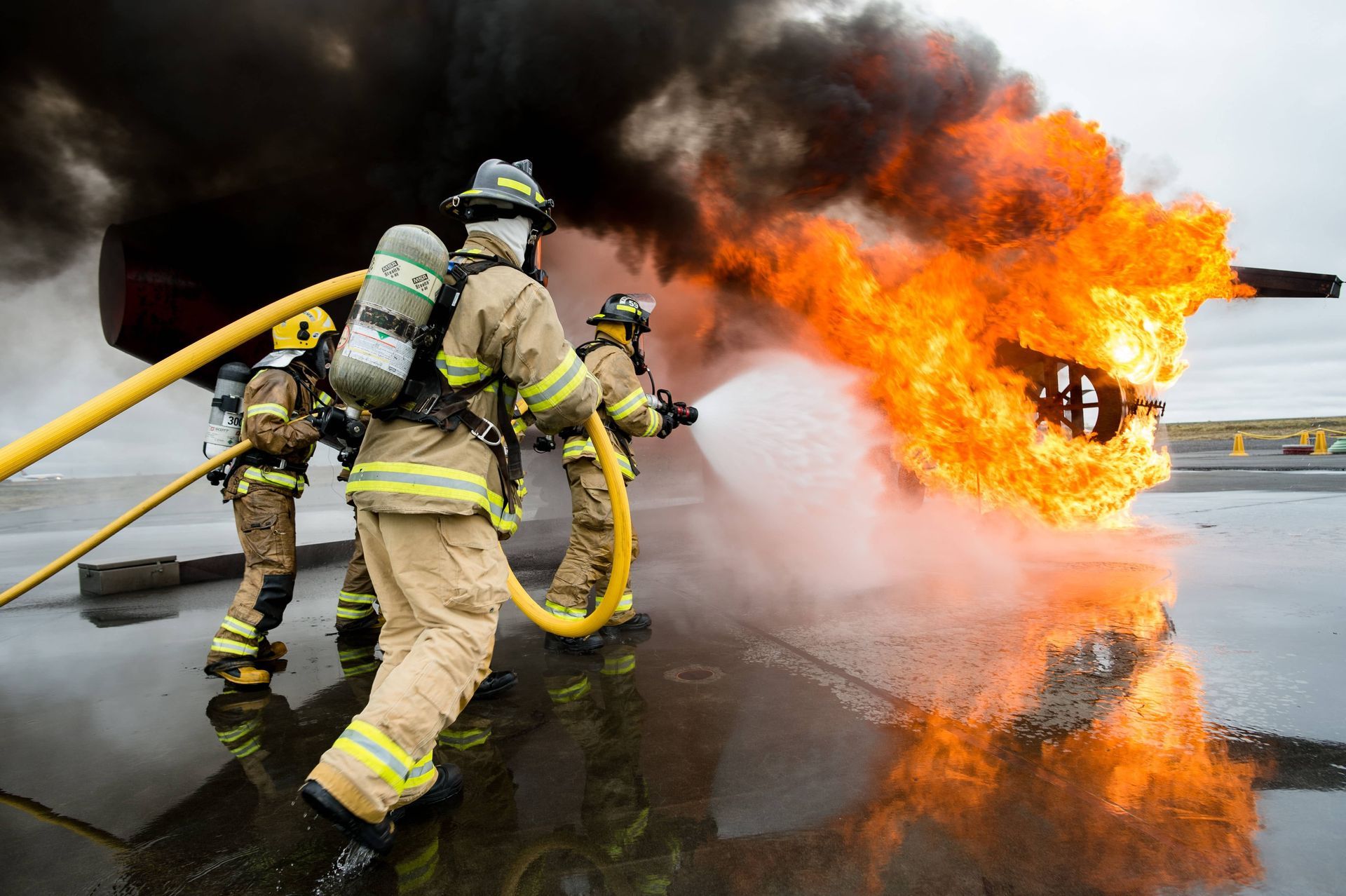 A group of firefighters are fighting a fire with a hose.