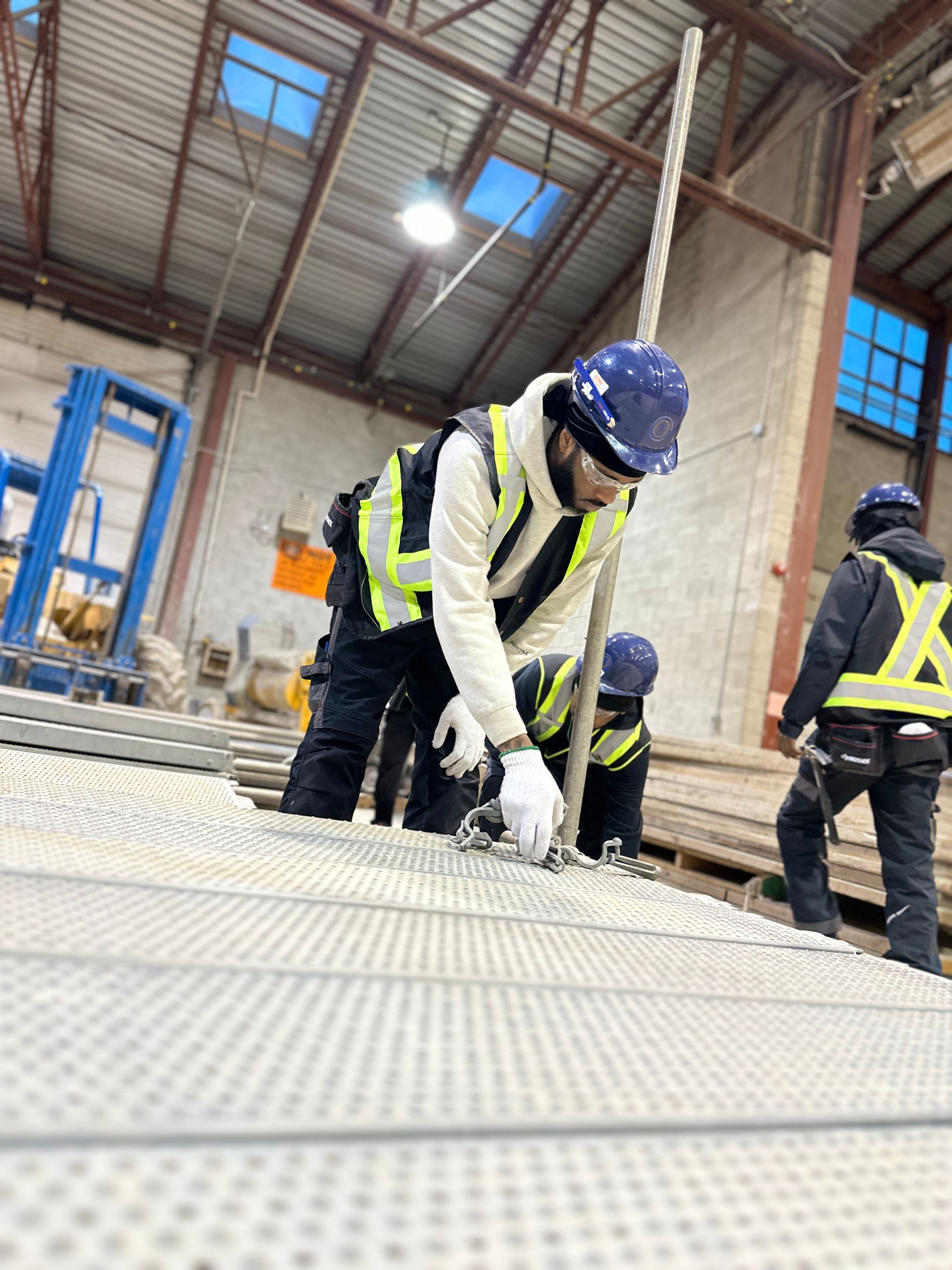 A group of construction workers are working on a metal structure in a warehouse.