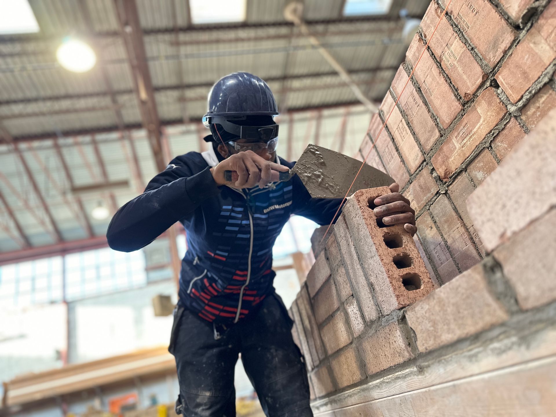 a man is laying bricks on a wall in a building