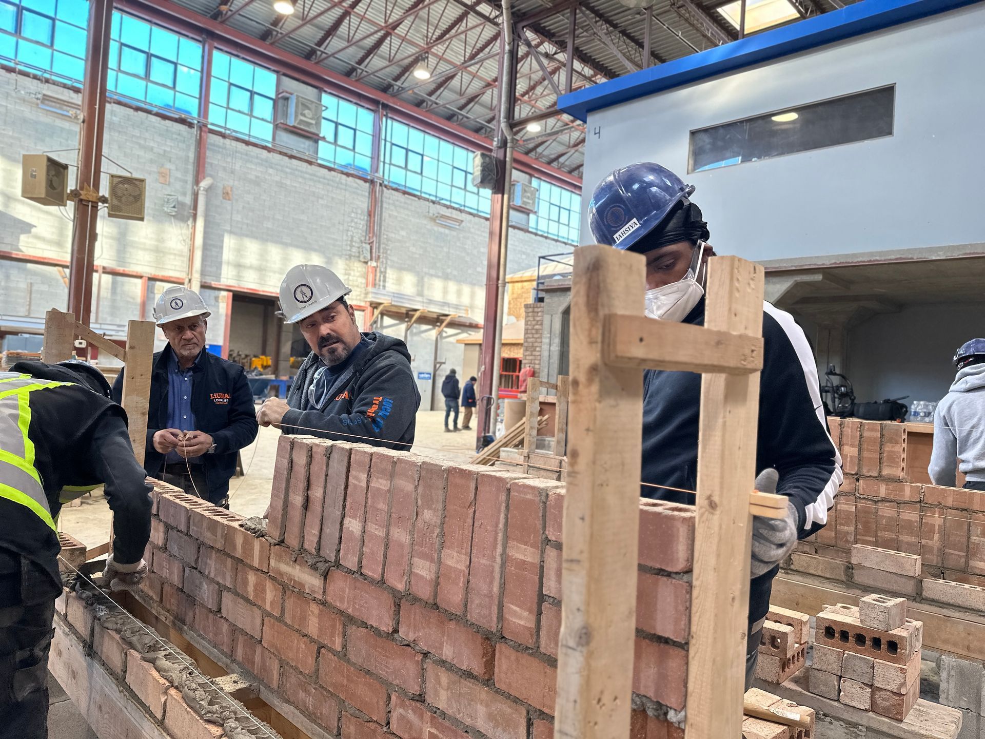 A group of construction workers are working on a brick wall.