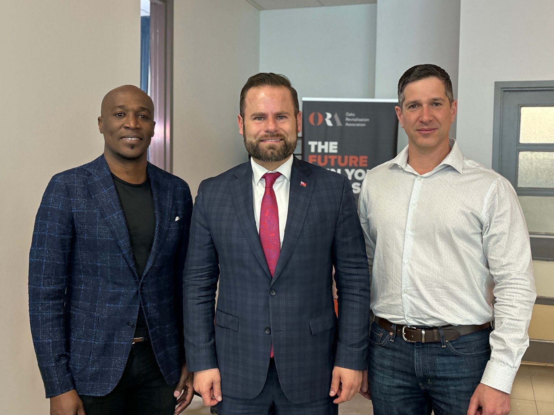 Three men in suits and ties are standing next to each other, posing for a photo