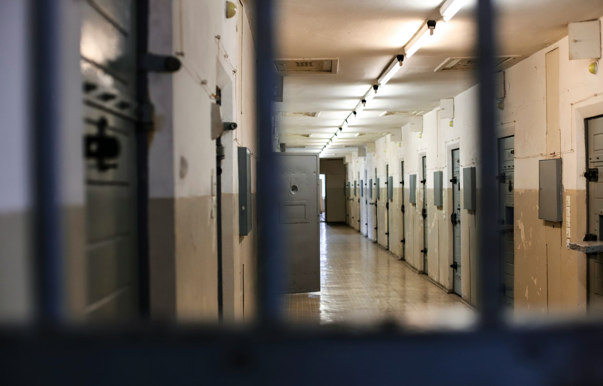 a long hallway in a prison with a row of cells