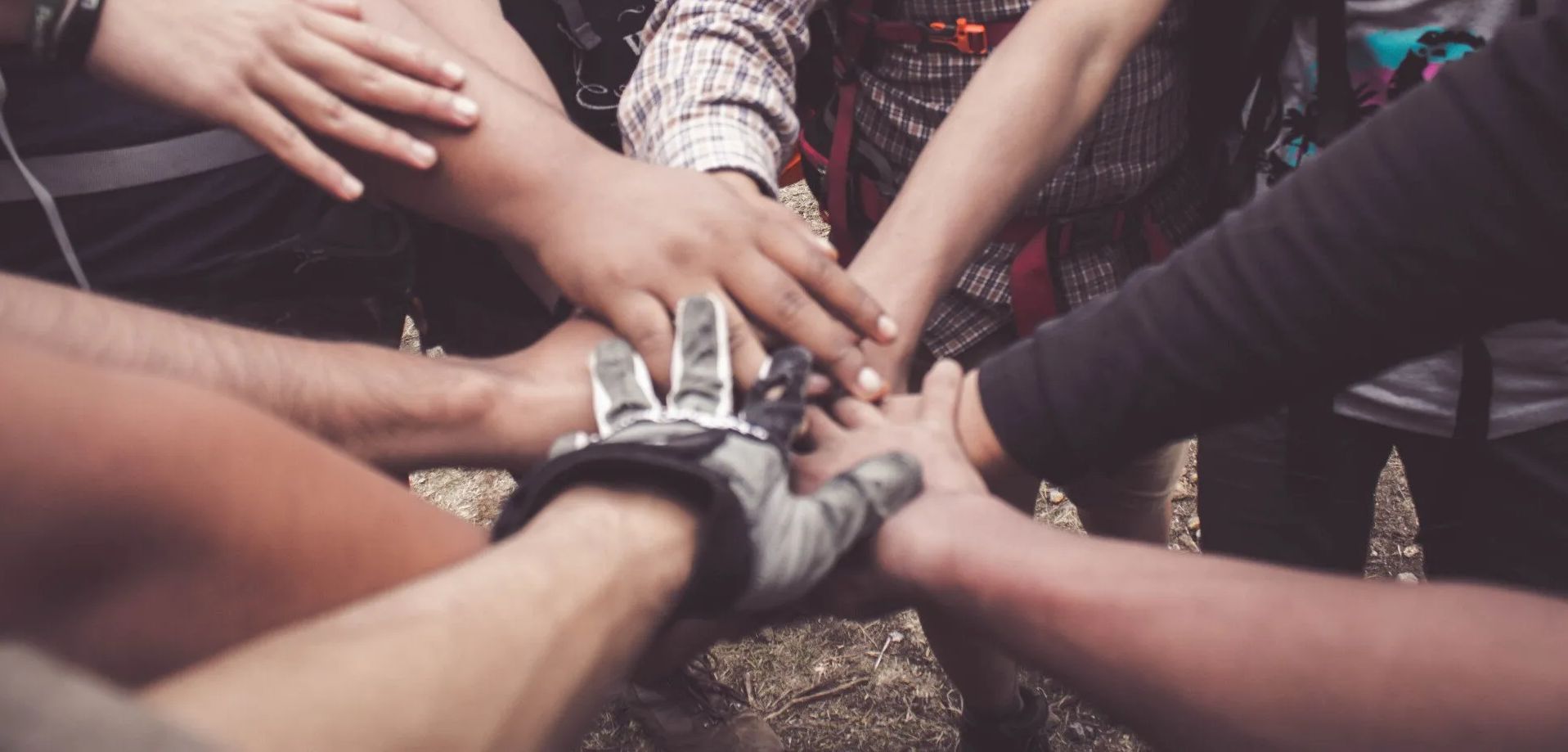 A group of people are putting their hands together in a circle.